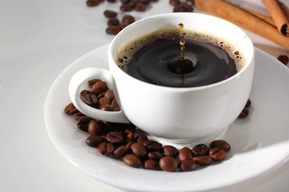 Чашка с кофе, кофейные зерна на блюдце