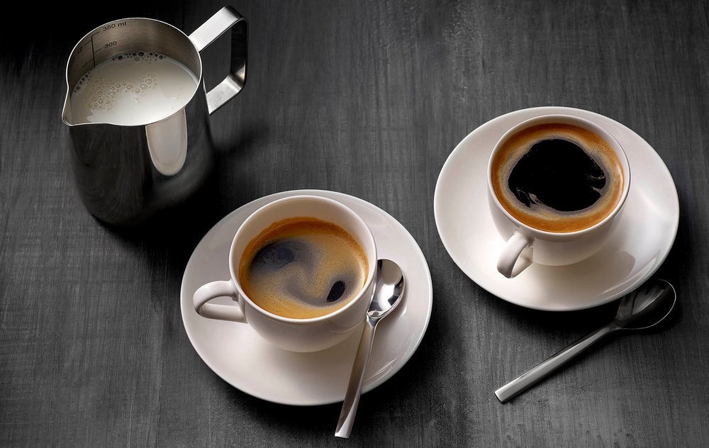 Чашки с кофе на блюдцах, чайные ложки, сливки в кувшине