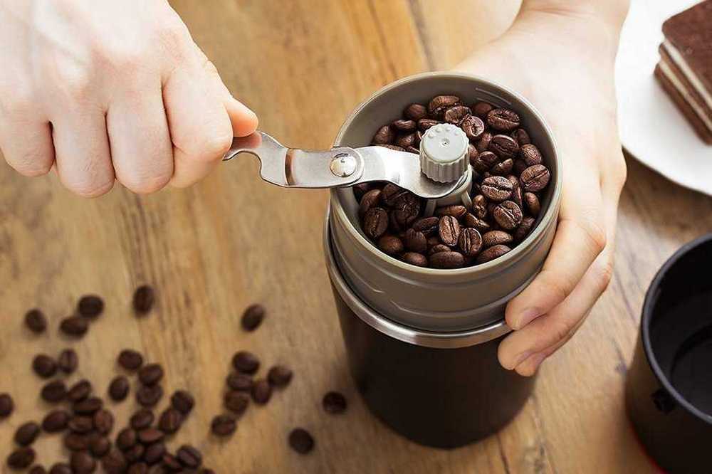 Кофейные зерна, кофемолка в руках