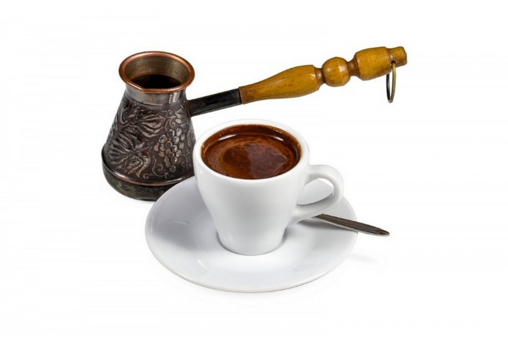 Чашка с кофе на блюдце возле турки